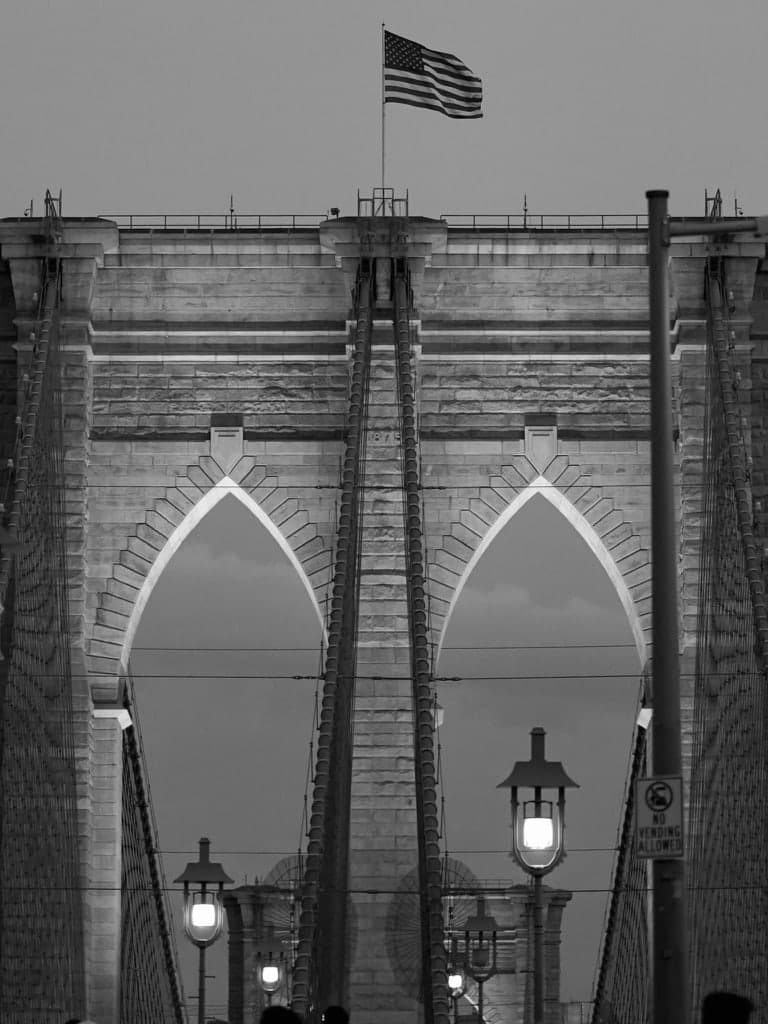 Steinbögen der Brooklyn Bridge mit amerikanischer Flagge