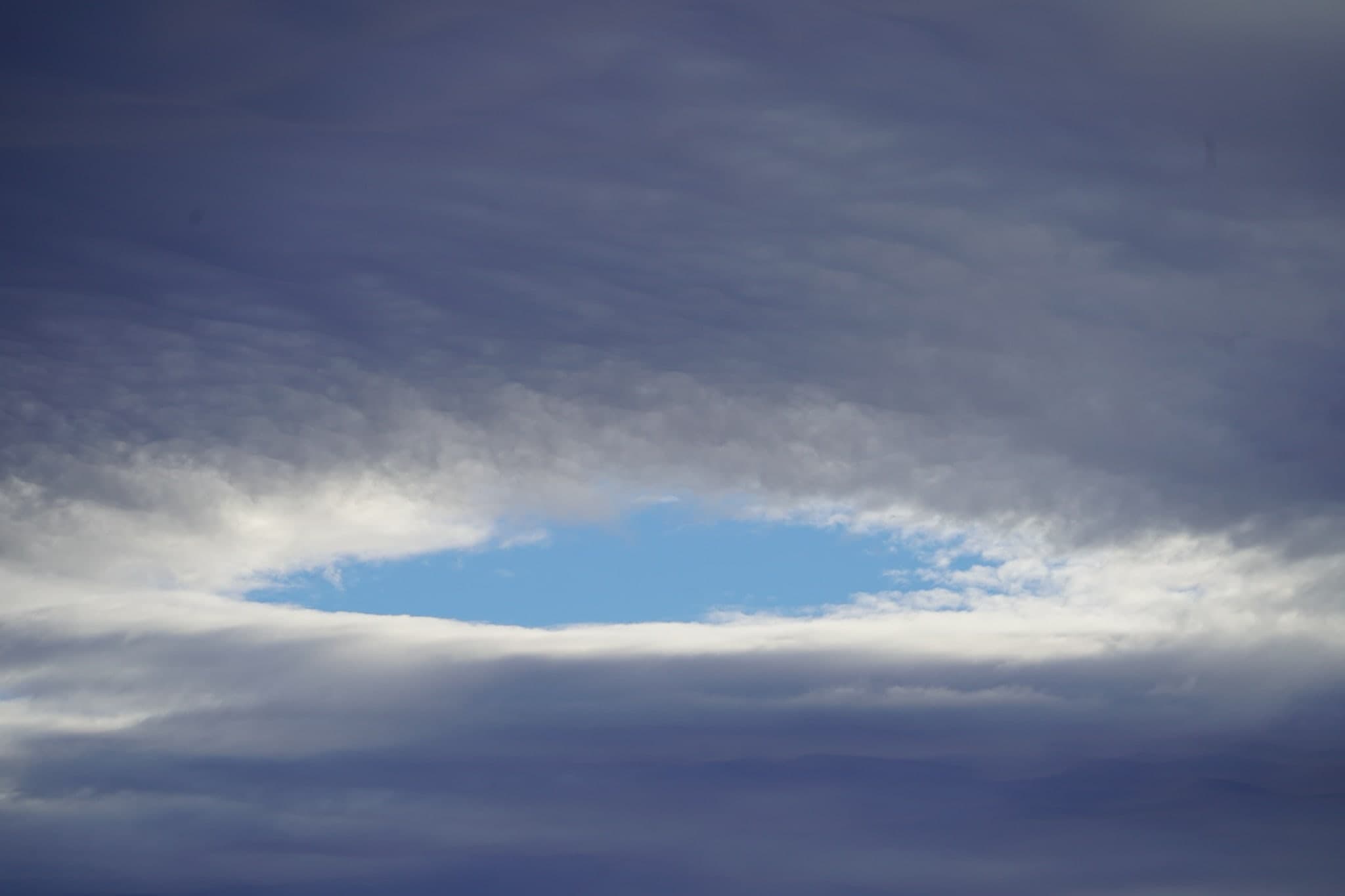 Blaue Öffnung in einer dichten Wolkendecke