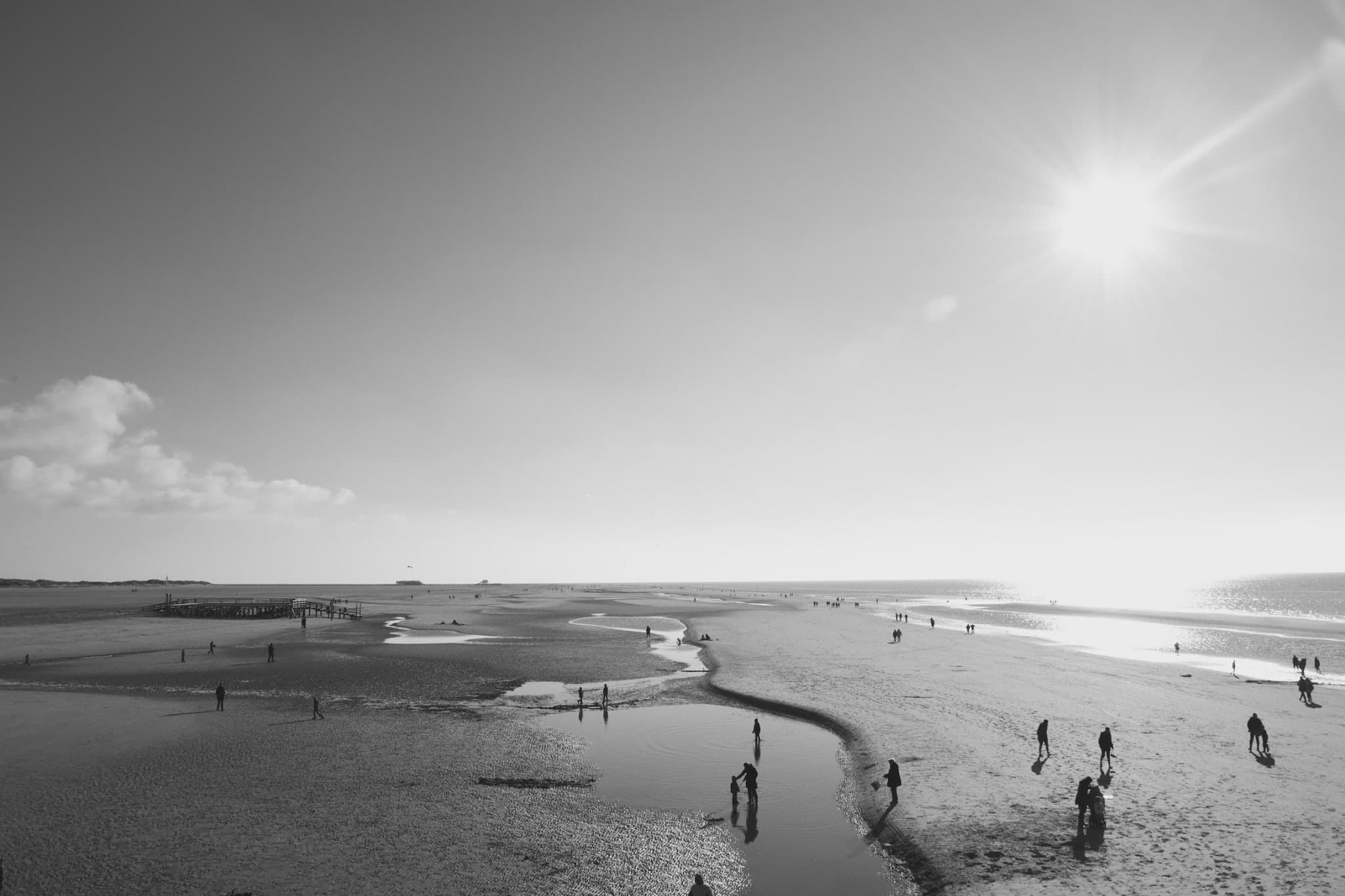 Weite Gezeitenküste mit kleinen Figuren am Strand