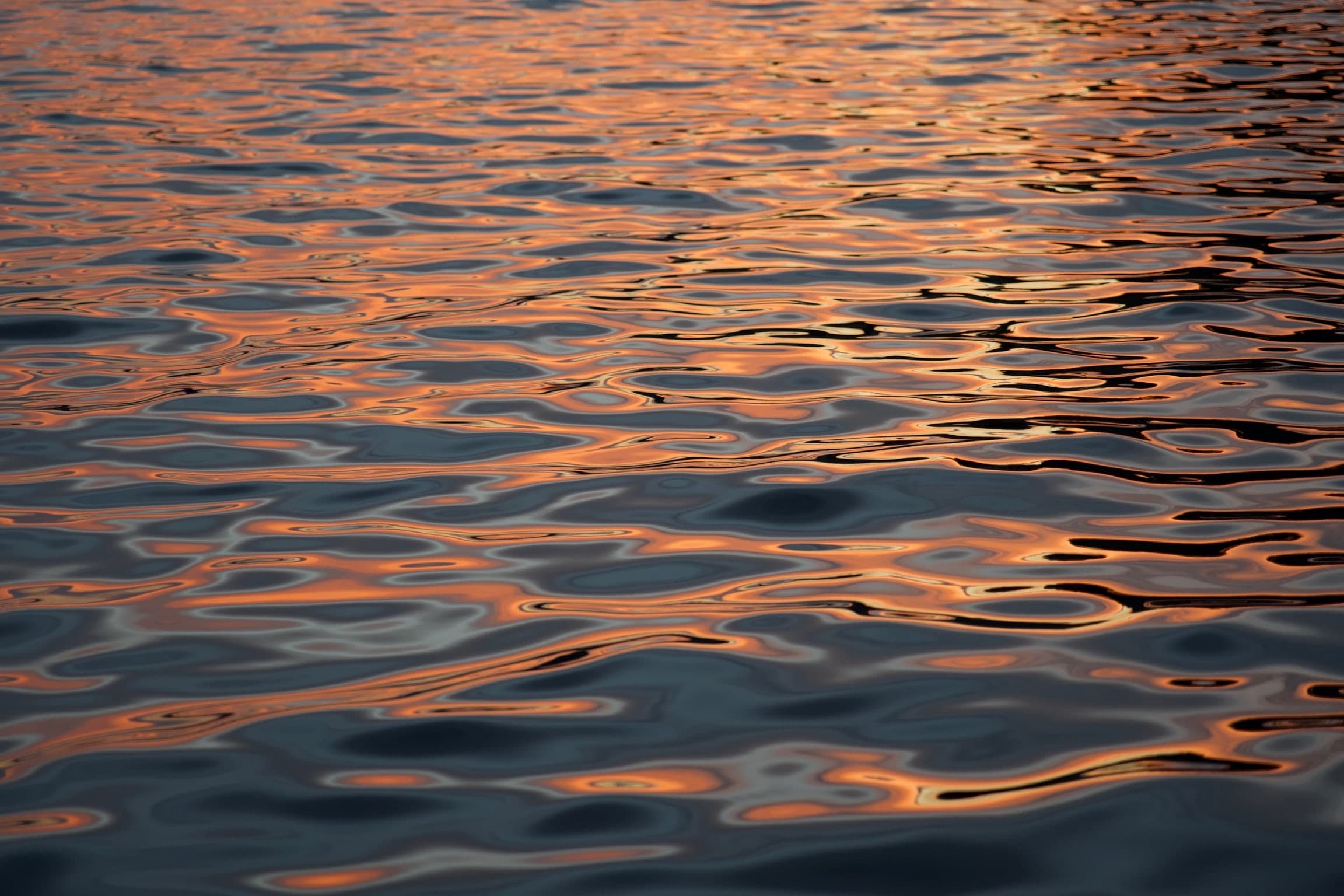 Wasseroberfläche mit warmen kupferfarbenen Reflexen