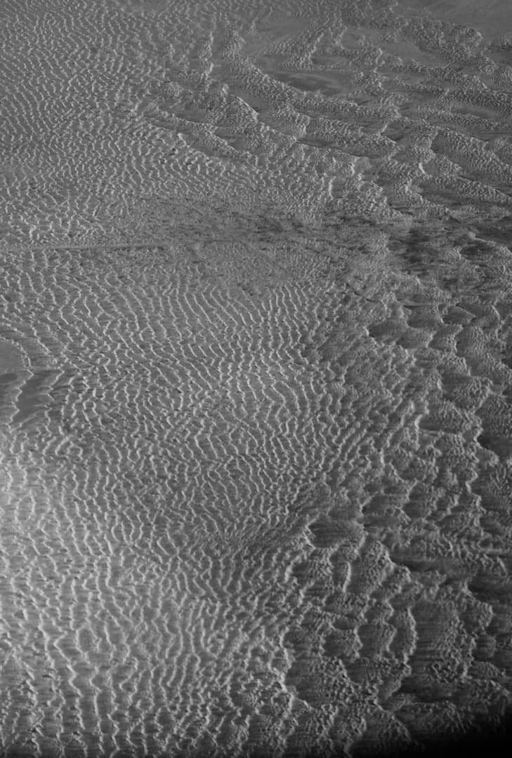 Vom Wind gezeichnete Sandrippel und Fußspuren in Schwarz-Weiß